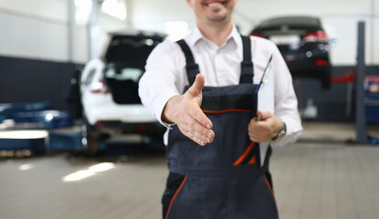 Fototapeta premium Focus on smart man hand reaching for firm handshake with someone and holding important paper folder with information about different autos. Machinery repairman concept