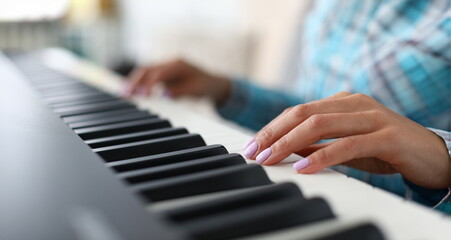 Close-up of female hands playing synthesizer in music workshop. Professional cute pianist creating...