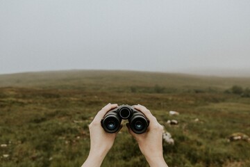 Bird watcher holding binoculars in Scottish Highlands