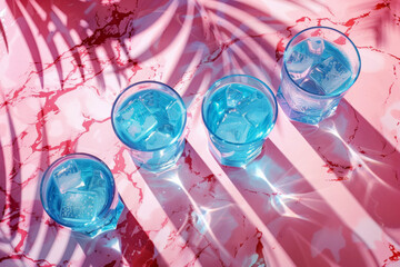 Blue cocktails with ice cubes on a pink background.