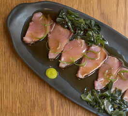 Overhead view of bonito sashimi fillets with wasabi sauce and seaweed