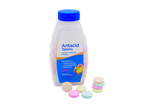 Chewable Antacid tablets for medication, health care concept. Close up of of chewable antacid acid reducer tablets with fruit flavor and plastic container bottle, Isolated on white background