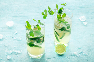 Mojito cocktail. Summer cold drink with lime, fresh mint, and ice. Cool beverage, side view on a blue background