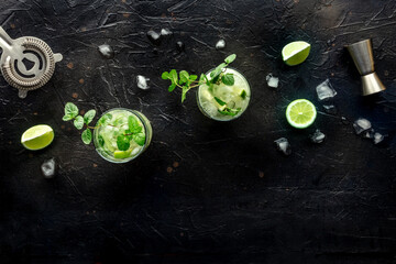 Mojito cocktail. Summer cold drink with lime, fresh mint, and ice. Cool beverage on a black background, shot from above with a place for text