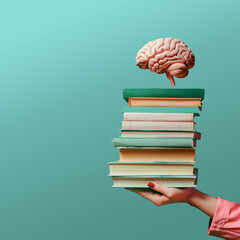 Female hand holding a stack of books with human brain on blue background with copy space. Concept of education and going back to school.