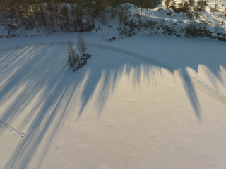 Nature landscape of Estonia in winter. The forest casts long shadows on the frozen lake.