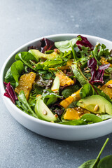 Fresh salad Organic avocado and spinach leaves  with orange and olive oil in a white plate. vegetarian dish