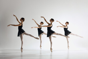 Young teen girls, graceful ballerinas in back costumes standing on pointe, training, performing over grey background. Artistic expression. Concept of ballet art, dance studio, classical style, youth