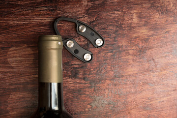 Wine bottle and bottle opener on wooden background.