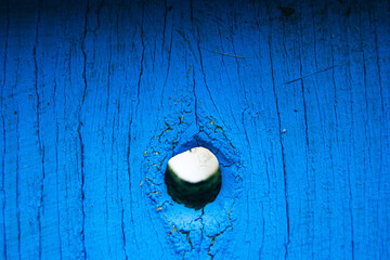 A close-up shot capturing the wood texture of blue-colored wooden gates, peephole. 