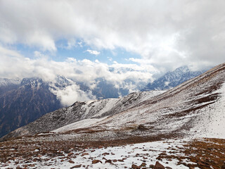 Snow-dusted mountain ridge with rugged terrain under a cloudy sky