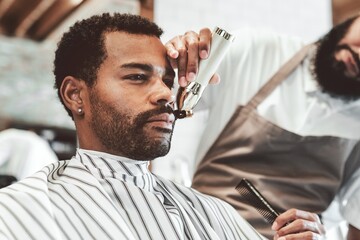 Customer getting a beard trim in a barber shop, small business