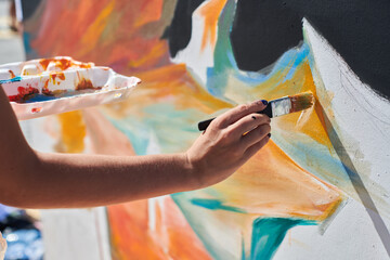 Female painter hand passionately paints picture with paintbrush for outdoor street exhibition using...