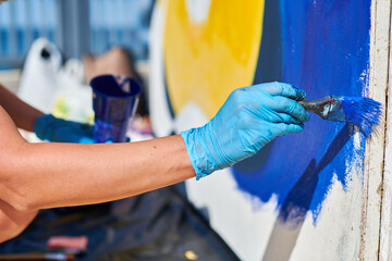Female painter hand passionately paints picture with paintbrush for outdoor street exhibition using...