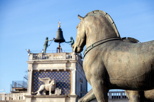View of Horses of Saint Mark and the winged lion at the Clock Tower defocused in the background on a beautiful sunny day in Venice; Italy