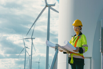 female engineer working outdoor with safety at wind turbines clean energy power station background, worker people with renewable energy technology for future concept. - 801166276
