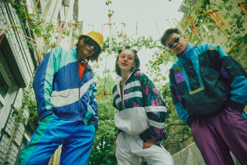 Sporty and stylish. Young people, boys and girls wearing 90s style tracksuit, accessories, posing outdoors over greenery background. Concept of 90s, fashion, youth culture, old-style trends