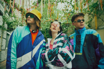 Throwback fashion. Stylish boys and girl wearing typical 90s outfits, tracksuits and accessories, posing outdoors. Vintage athletic wear. Concept of 90s, fashion, youth culture, old-style trends
