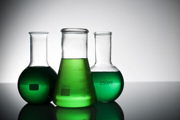 Three glass flask placed in a laboratory table with green liquid