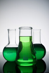 Three glass flask placed in a laboratory table with green liquid