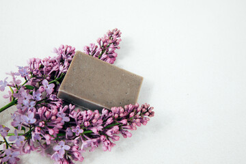A bar of natural soap with lilac flowers on a concrete background. Cosmetics from natural ingredients, herb. Top view