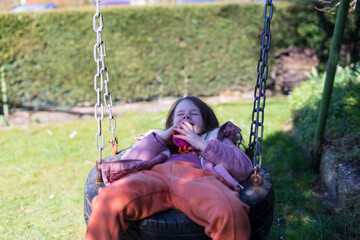 Little girl having fun on a swing in the park on a sunny day