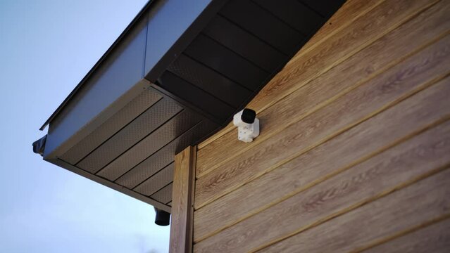 CCTV security camera system located under roof of wooden cottage. Modern equipment ensures safety protecting owners from potential threats