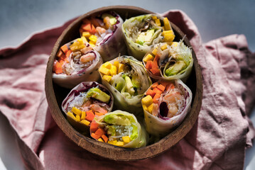 A bowl of colorful spring rolls filled with a variety of fresh vegetables