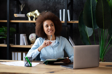 Young concerned African American businesswoman sitting at desk  in contemporary corporation office....