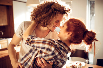 Happy couple embracing and kissing in sunny kitchen