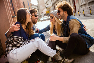 Group of trendy young friends laughing together on a city street