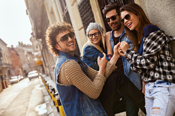 Group of trendy young friends laughing together on a city street