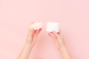 Round jar of cosmetic cream in hand on pink background. Cosmetics beauty mockup for product branding