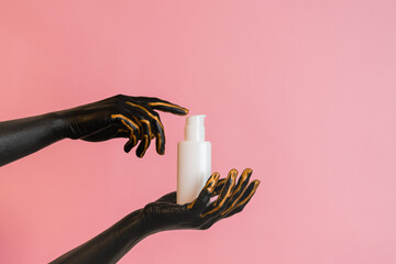 Cosmetic glass tube in hands with black paint on her skin. Presenting luxury skincare products....