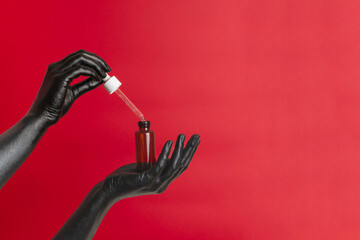Black painted hands on her skin with cosmetic glass tube. Luxury product cosmetic advertising....
