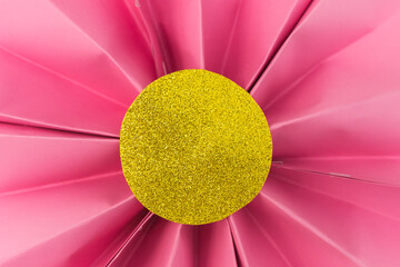 Folded pink paper flower with gold glitter center. Crafts for decoration.