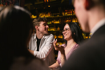 Young people talk in relaxed atmosphere and drink spirits cocktails. Relax in atmospheric nightclub...