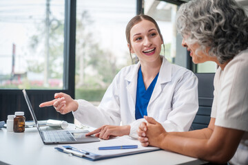 Monthly health check-ups and counseling sessions are provided to an elderly Asian woman by a Caucasian female caregiver, offering support, advice, and motivation.