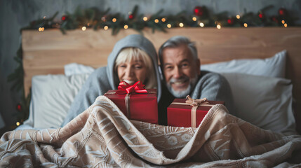 Mature couple with Christmas gift boxes hiding 