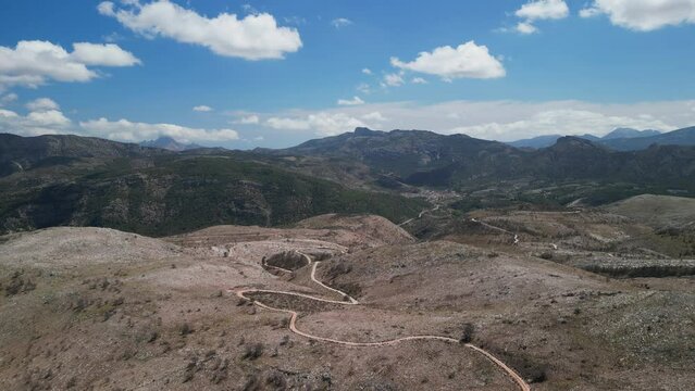 Aerial drone footage over mountains and gravel roads over Castell de Castells, Alicante region, Spain.