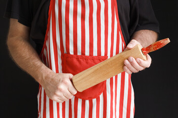 An angry and impatient baker brandishing a wooden rolling pin - obrazy, fototapety, plakaty