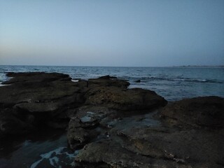 A calm beach landscape at sunset, with the sky and ocean coming together at the horizon.
