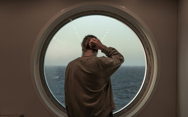 man looking out the ship's window