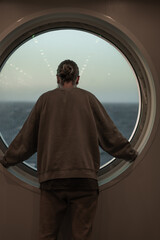man looking out the ship's window