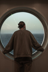man looking out the ship's window