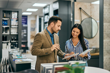 Focused salesman helping a female to choose the right ceramic tiles for her home.