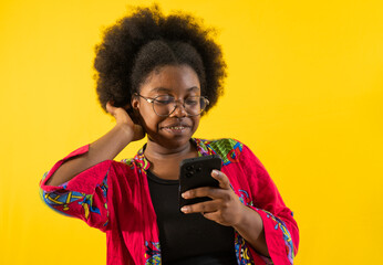 mujer afrolatina usando lentes y ropa colorida mientras interactúa con su teléfono móvil 