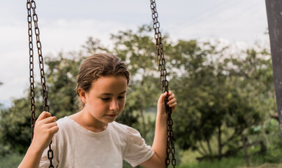 concepto de retrato de adolescente triste y pensativa montando columpio al aire libre 