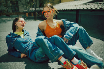 Young people, girls wearing denim clothes and and colorful accessories. Chilling on urban rooftop on a daytime. Concept of 90s, fashion, youth culture, old-style trends