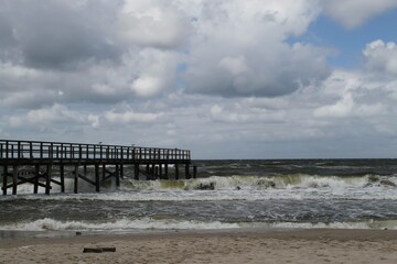 stormy beach scene featuring a wooden pier